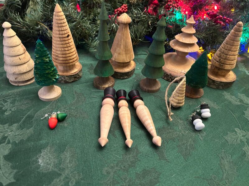 Seasonal collection. A grouping of wooden tree forms, hanging ornaments, and small seasonal decorations.