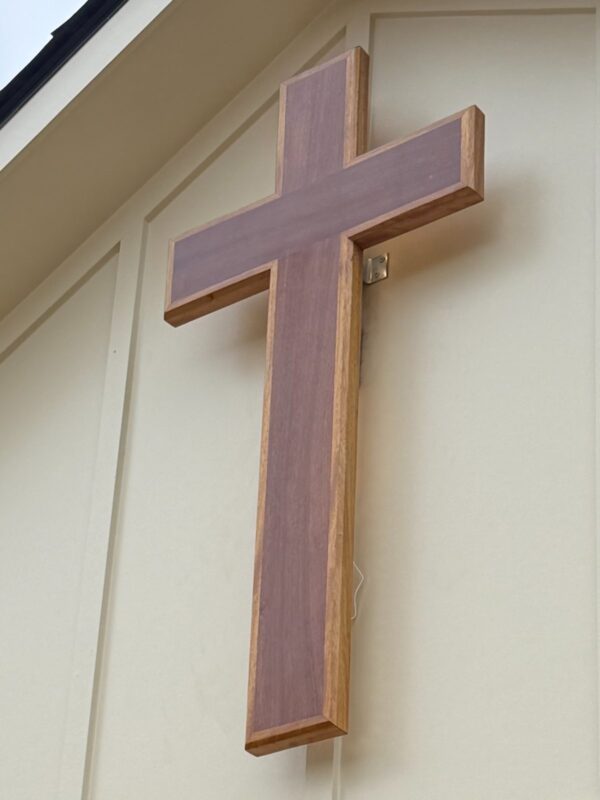Wooden cross project. Wooden cross installed on the front of a building, with no people in view.