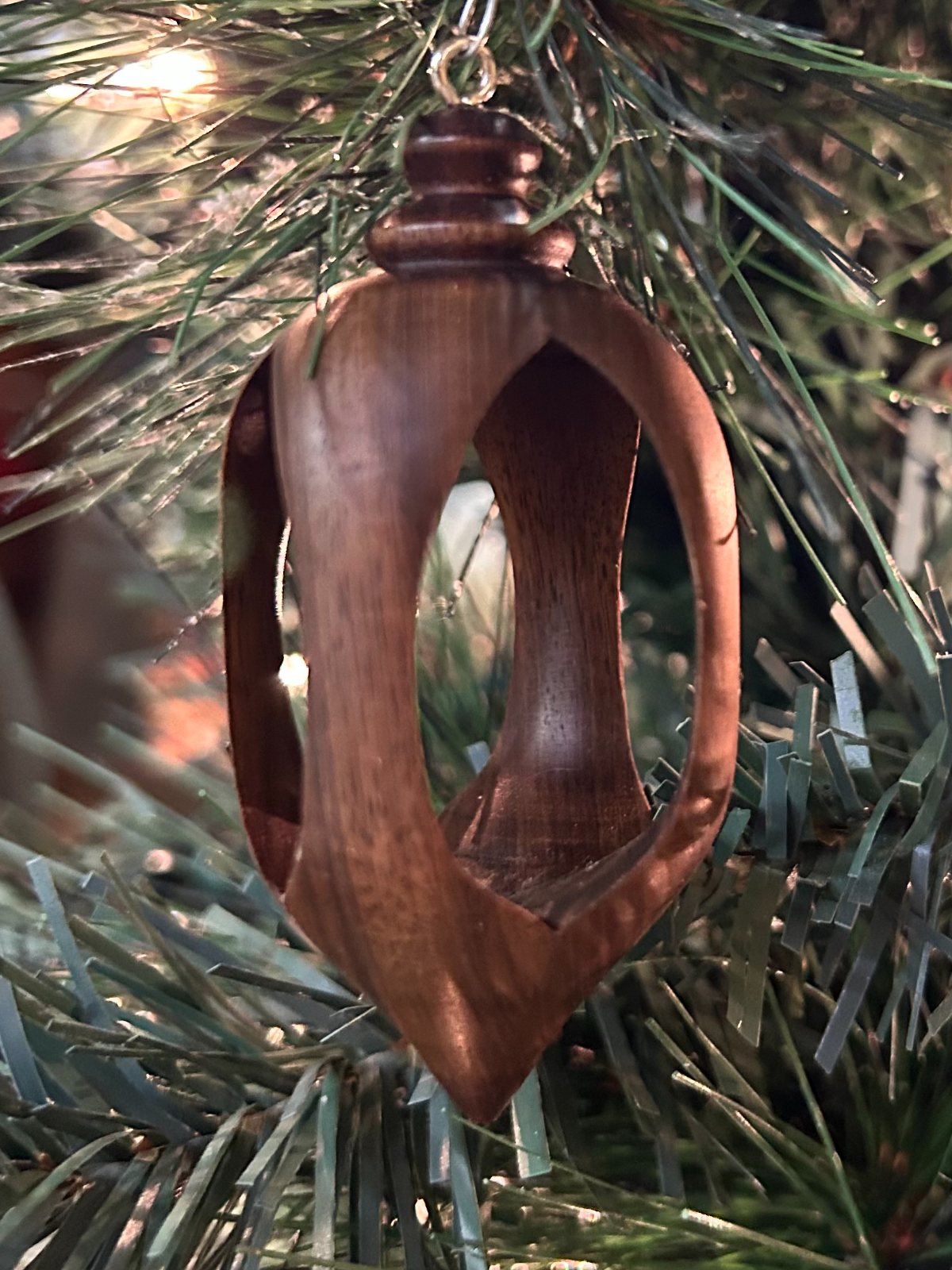 Open ornament. Dark open-frame wooden ornament hanging in a tree.