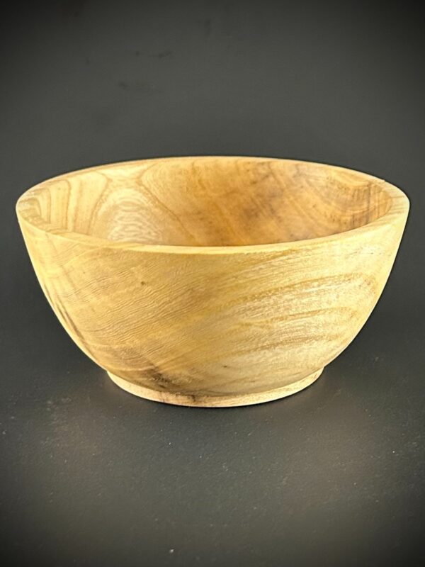 Pale-grain bowl. Pale rounded wooden bowl photographed against a dark background.