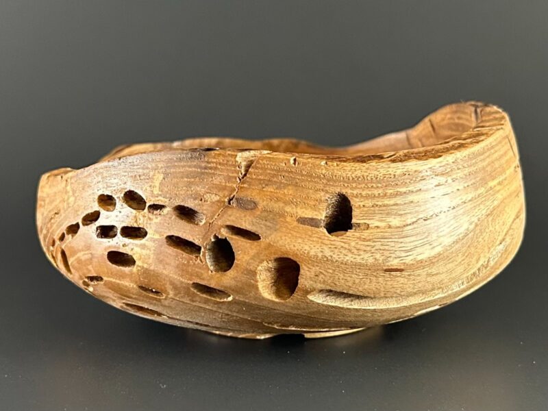 Open-textured bowl. Low wooden bowl with elongated openings and an uneven rim.
