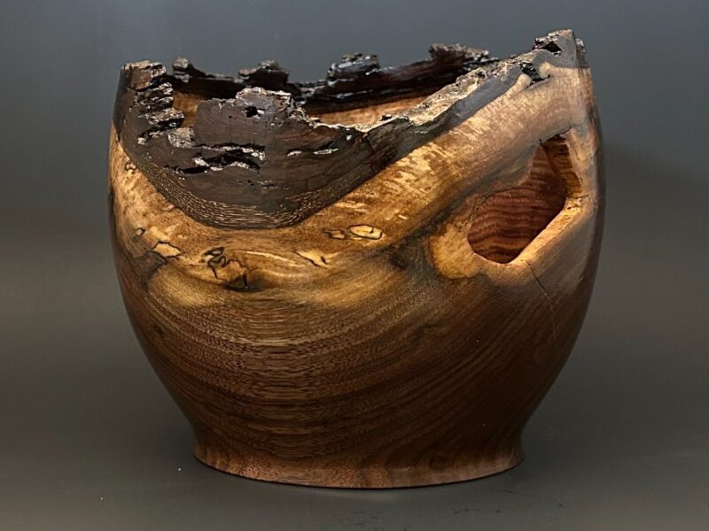 Rugged-rim vessel. Dark rounded vessel with a rugged, uneven upper edge and side openings.