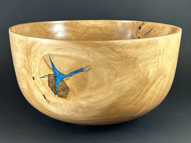 Blue-accent bowl. Pale wooden bowl with a small blue accent beside a natural dark mark.