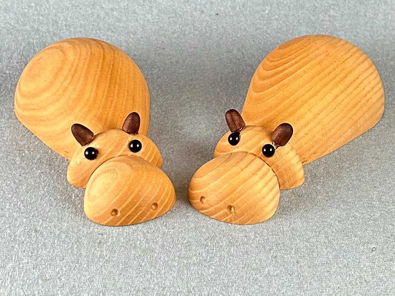 Small animal forms. Two small wooden animal figures with round eyes and broad upright tails.
