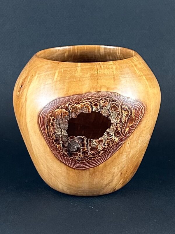 Knot-detail vessel. Rounded golden vessel with a large dark opening on its front.