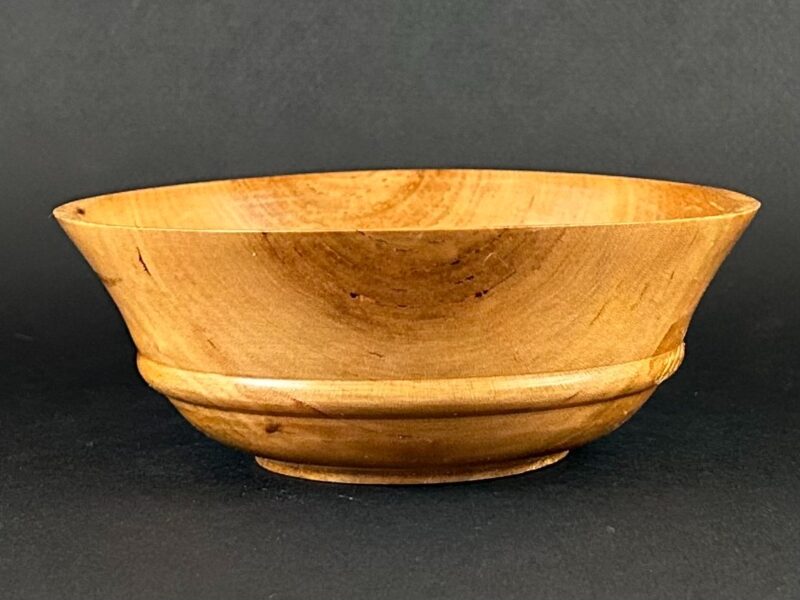 Stepped-foot bowl. Golden wooden bowl with a flared rim and stepped lower profile.