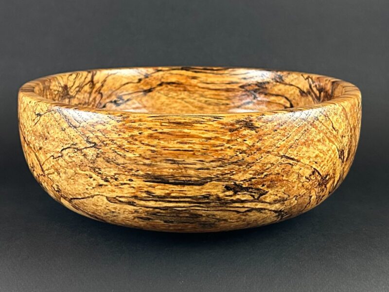 Dark-lined bowl. Rounded golden wooden bowl with dark branching grain lines.