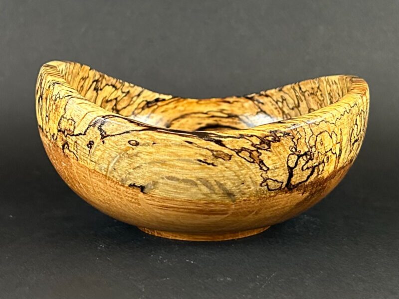 Curved pattern bowl. Golden bowl with a rising rim and dark traced grain.