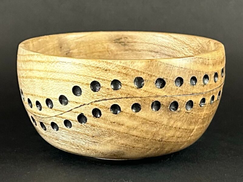 Pierced bowl. Pale wooden bowl with flowing rows of circular openings.