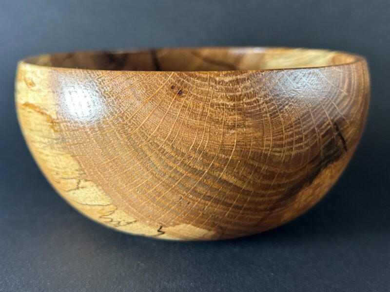 Character-grain bowl. Rounded wooden bowl with dark grain and a contrasting pale side.