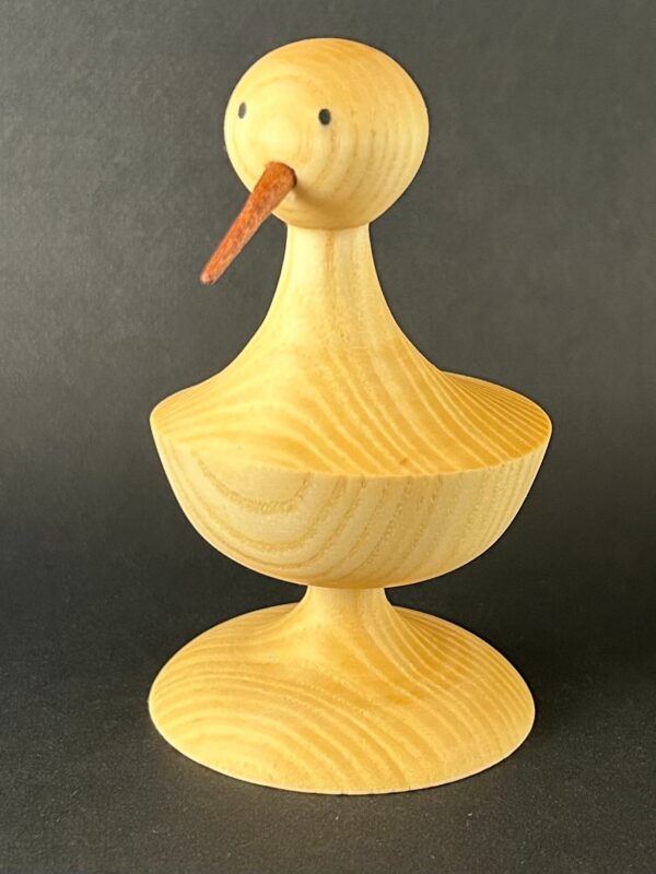Duck form. Pale wooden duck form with a small orange-toned beak.