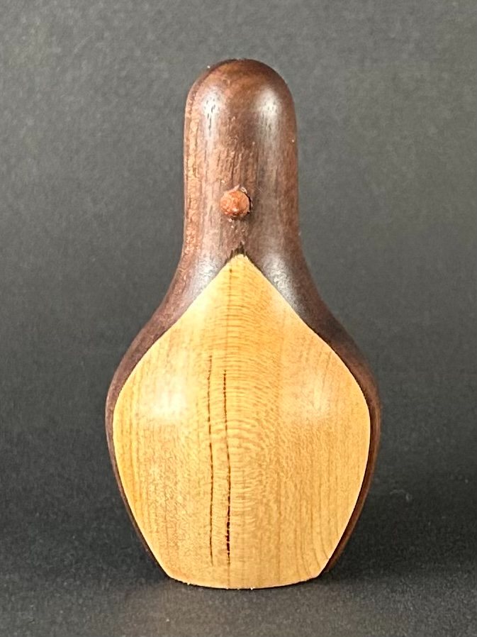 Penguin form. Upright wooden penguin form with a pale front and dark back.
