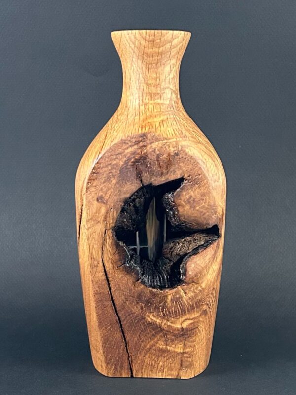 Natural-detail vessel. Tall wooden vessel with a narrow neck and a large dark opening.