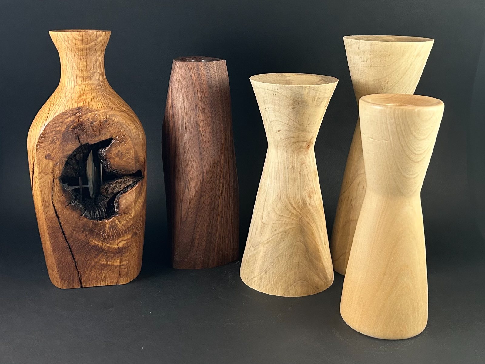 Vessel grouping. Group of tall wooden vessels and four pale hourglass-shaped forms.